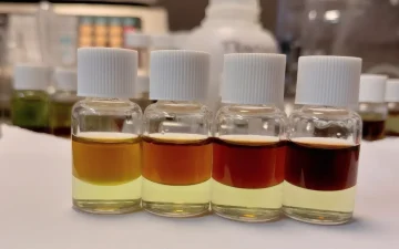 Vier referentieflesjes van de PRO Test voor cocaïnehoeveelheid, bovenlaag van oranje bij 25% tot bijna zwart bij 100%