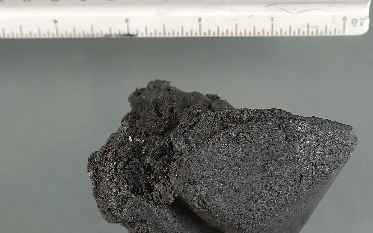 Een donkere plakkerige klomp black tar heroïne naast een liniaal