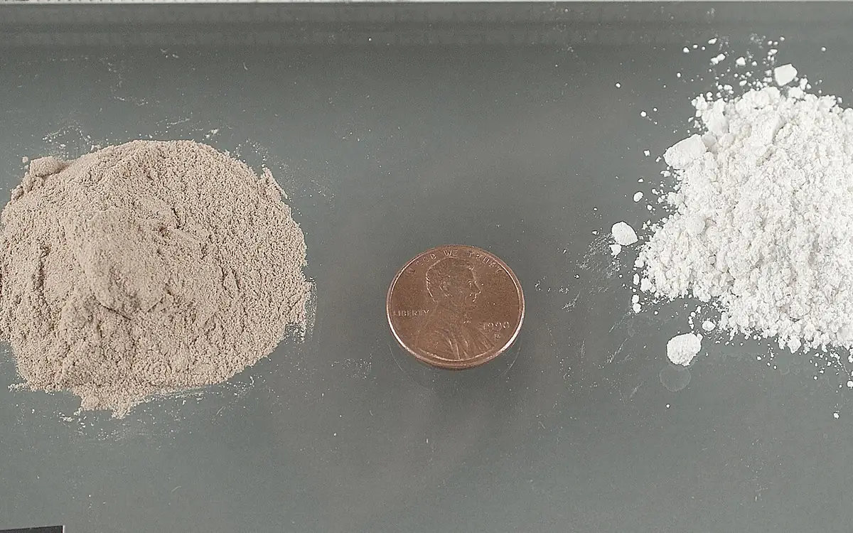 Een beige heroïnepoeder en een wit heroïnepoeder naast elkaar, met een muntstuk van één cent ertussen